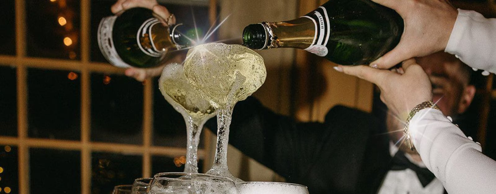 Two champagne bottles pouring champagne down glasses tower