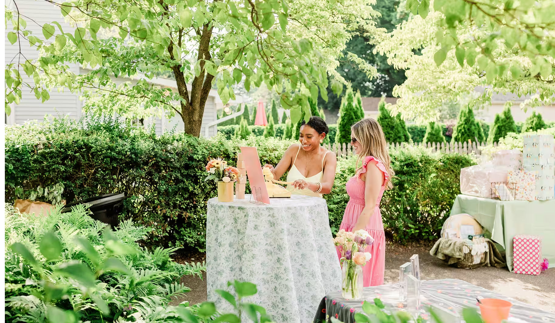Two woman in wedding garden speaking into audio guestbook