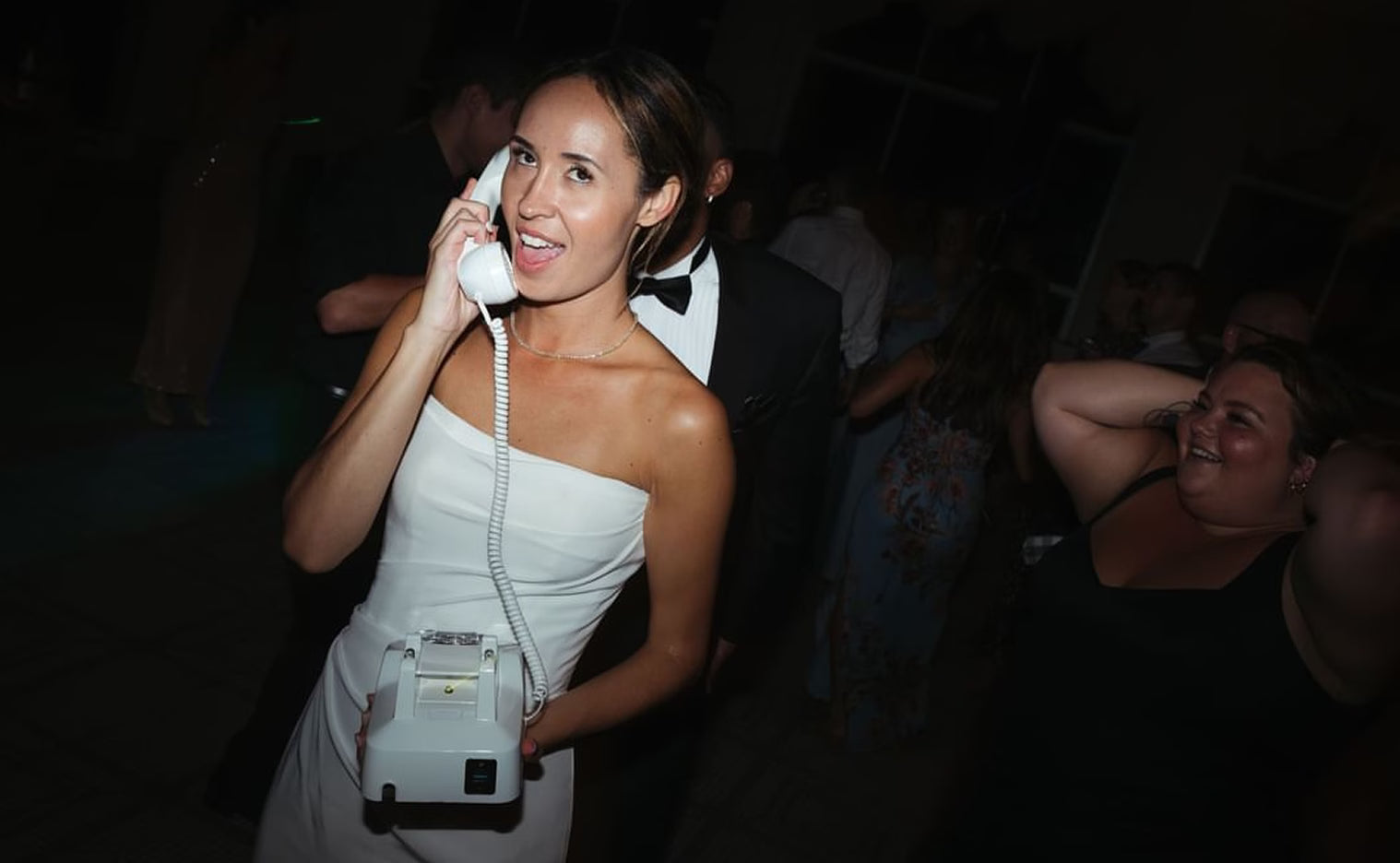 Bride in white dress speaking into white audio guestbook phone