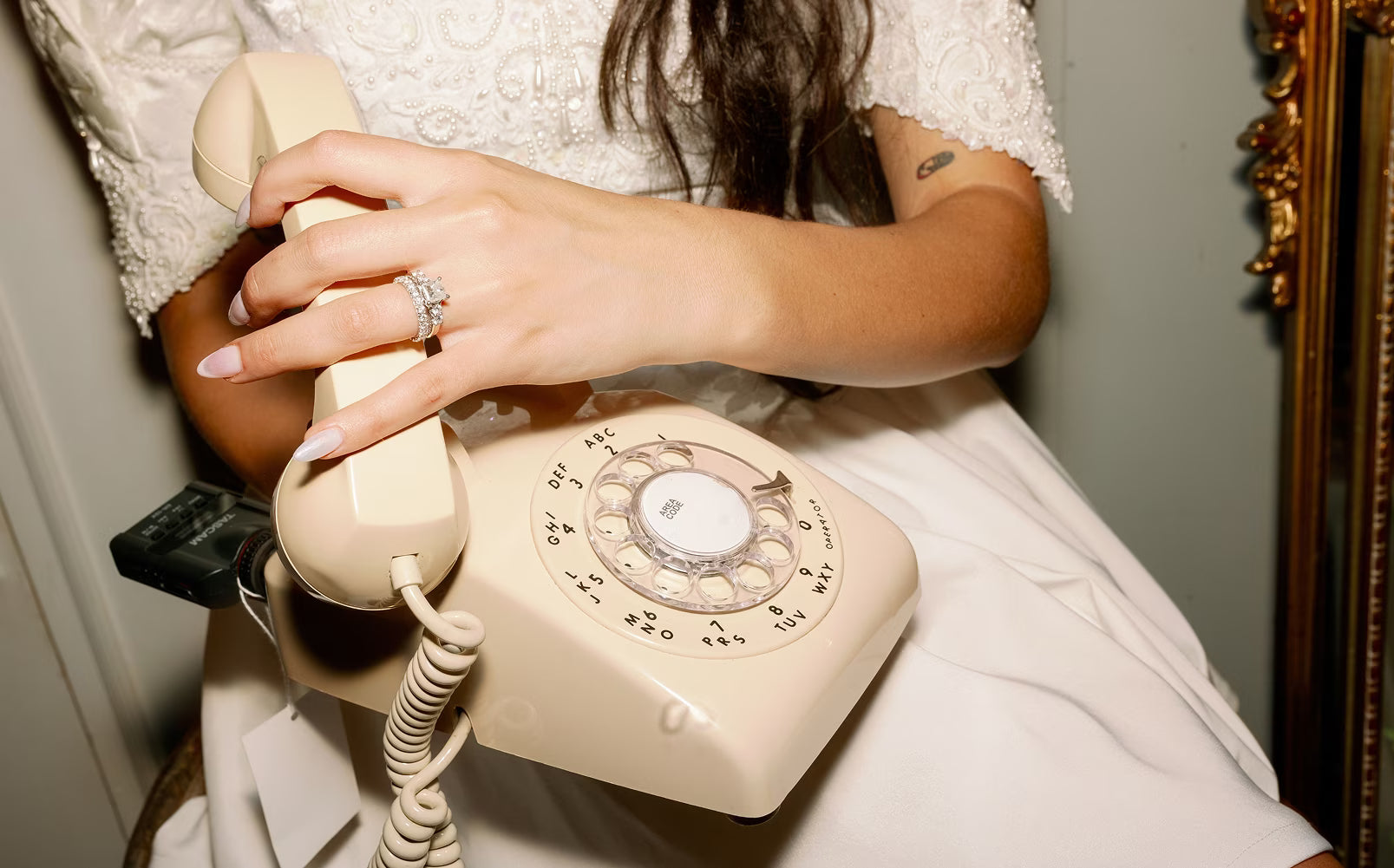 Womans hand reaching to answer a cream audio phone guestbook