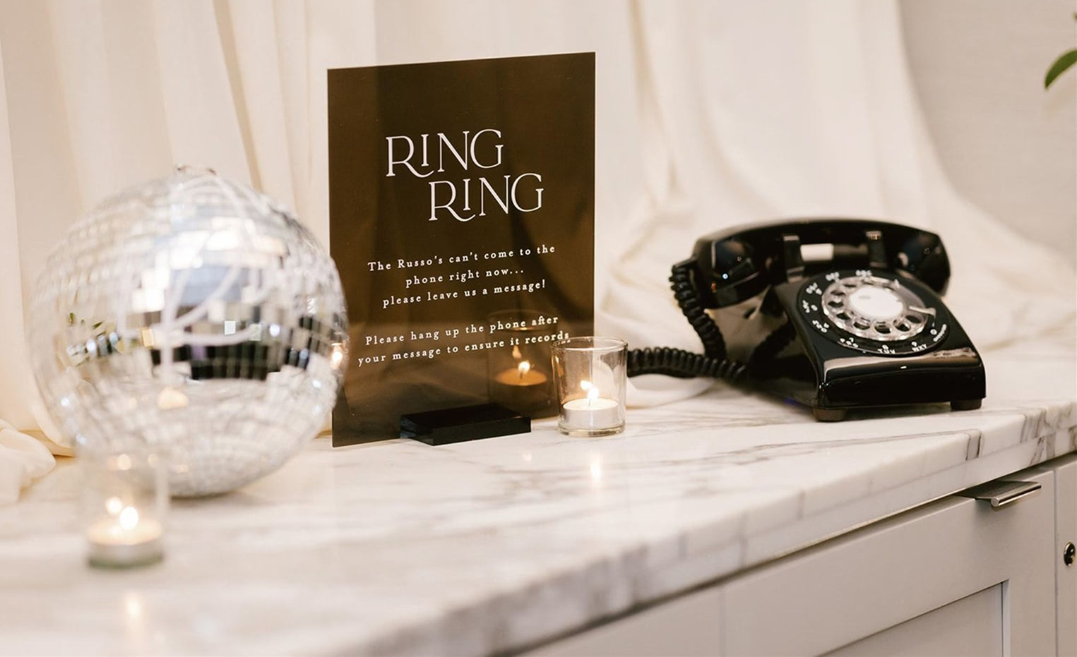 Black phone audio guest book next to signage on wedding table