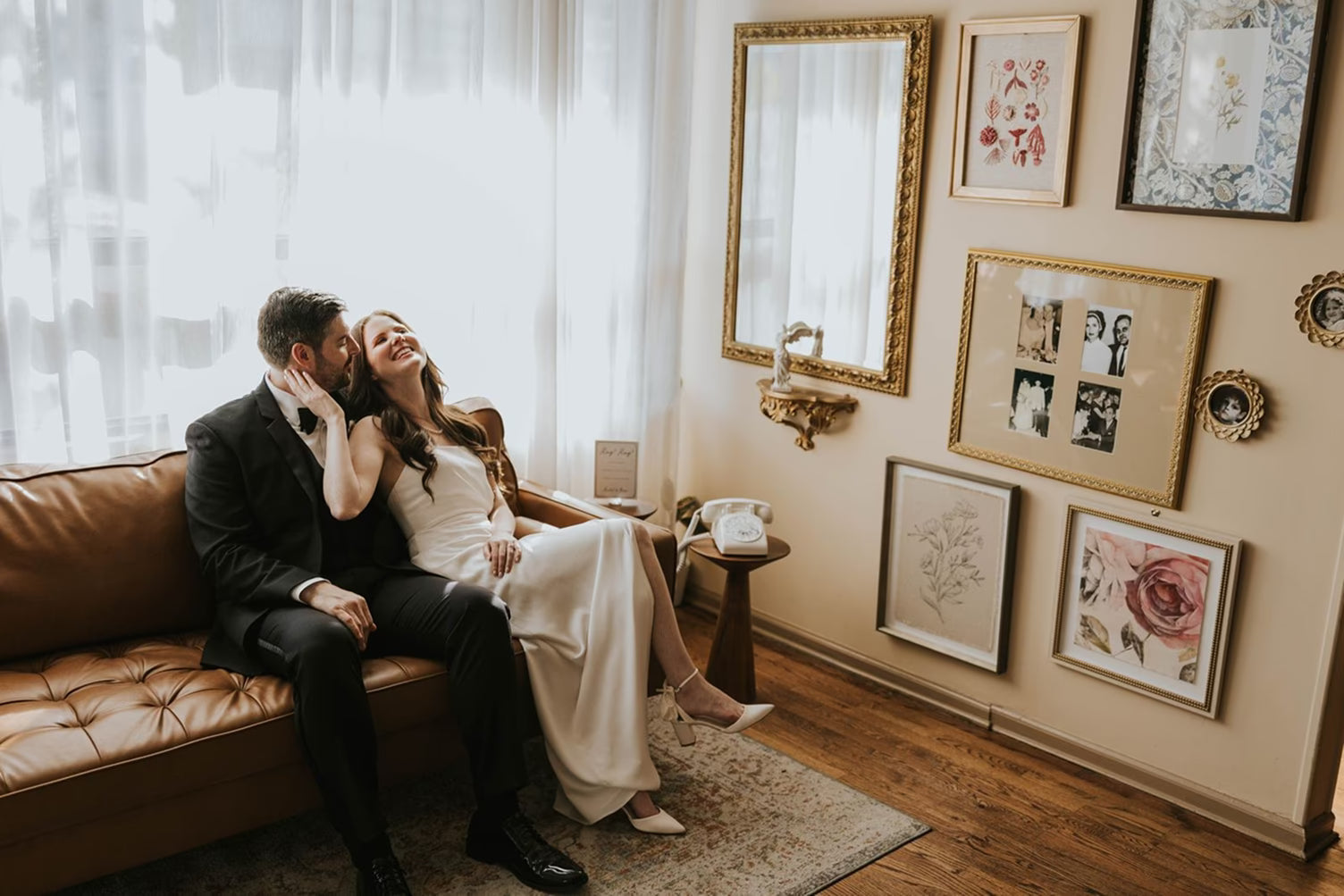 Bride and groom sitting on couch speaking into black wedding phone audio guest book