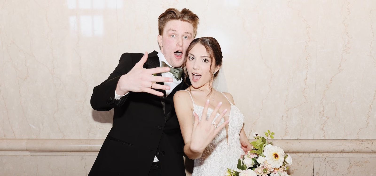A joyful bride and groom capture a fun wedding memory, playfully showing off their new rings with excited faces.