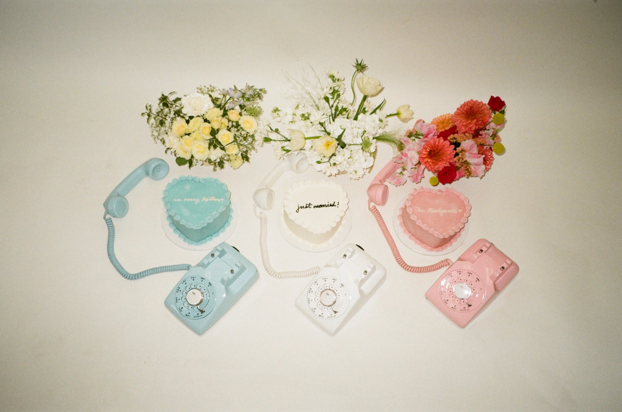 Blue white and pink rotary phones with florals and a wedding cake