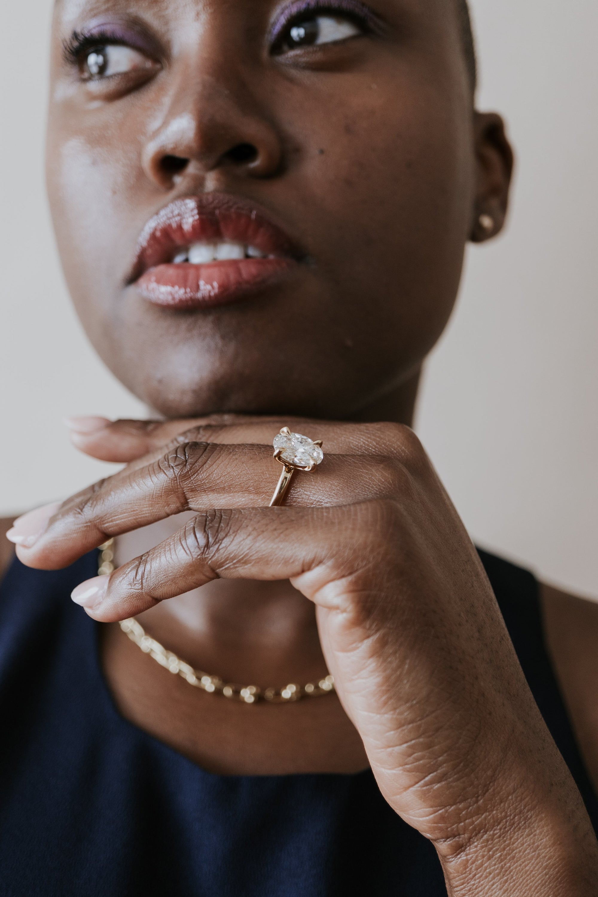 Woman poses with oval engagement ring on left hand