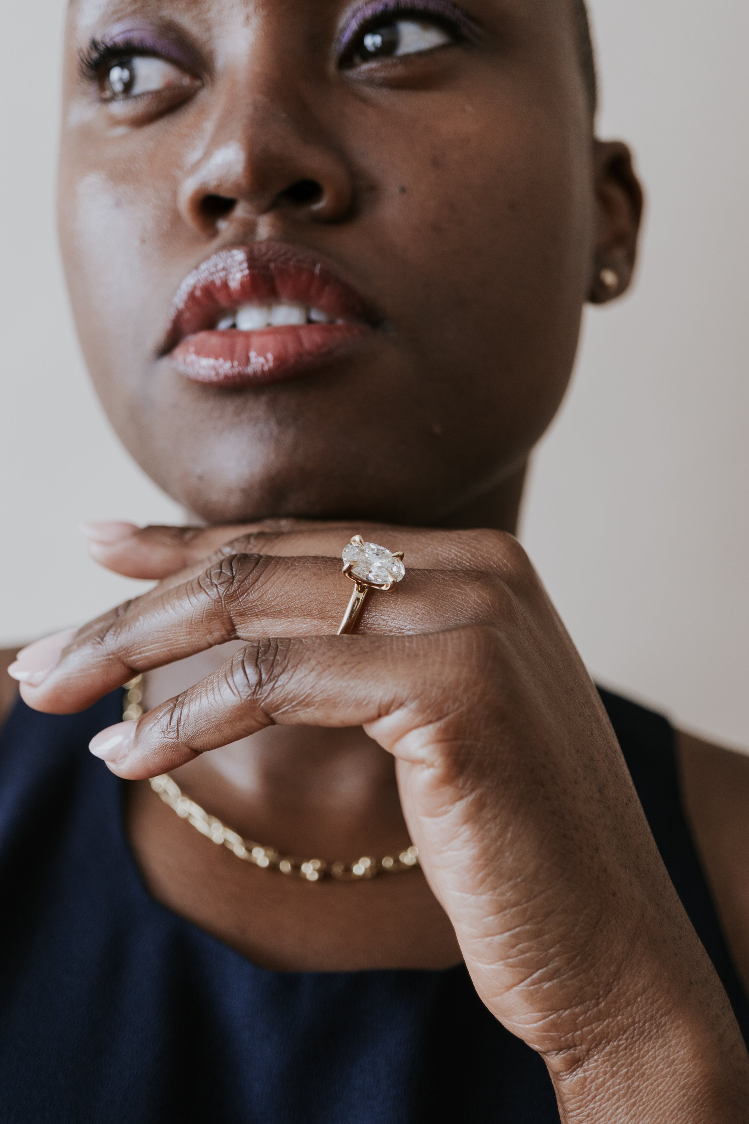 Woman poses with oval engagement ring on left hand