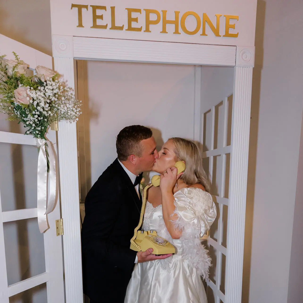 Man and woman in formal attire with a vintage yellow audio guestbook rotary phone in a room labeled Telephone.