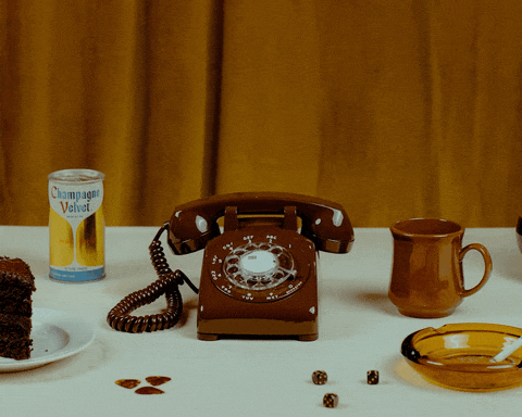 gif video showing a brown rotary phone and decorations around it.