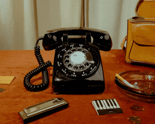 an animated gif video showing a black rotary phone audio guestbook and various decorations around it on a table and hands interacting with it.