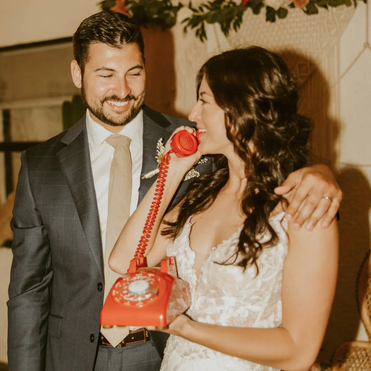 Man and woman in formal attire with a orange rotary phone.