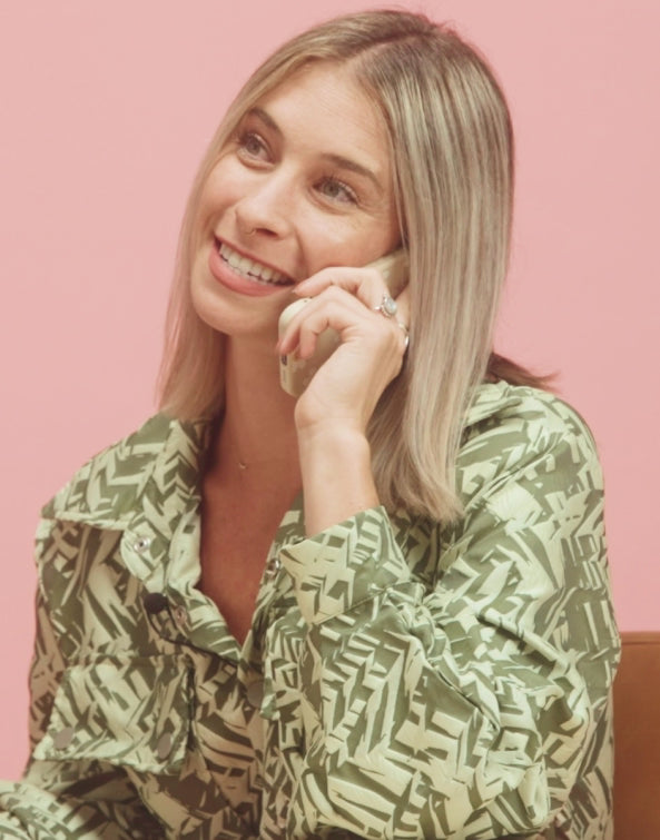 Woman in a patterned shirt against a pink background