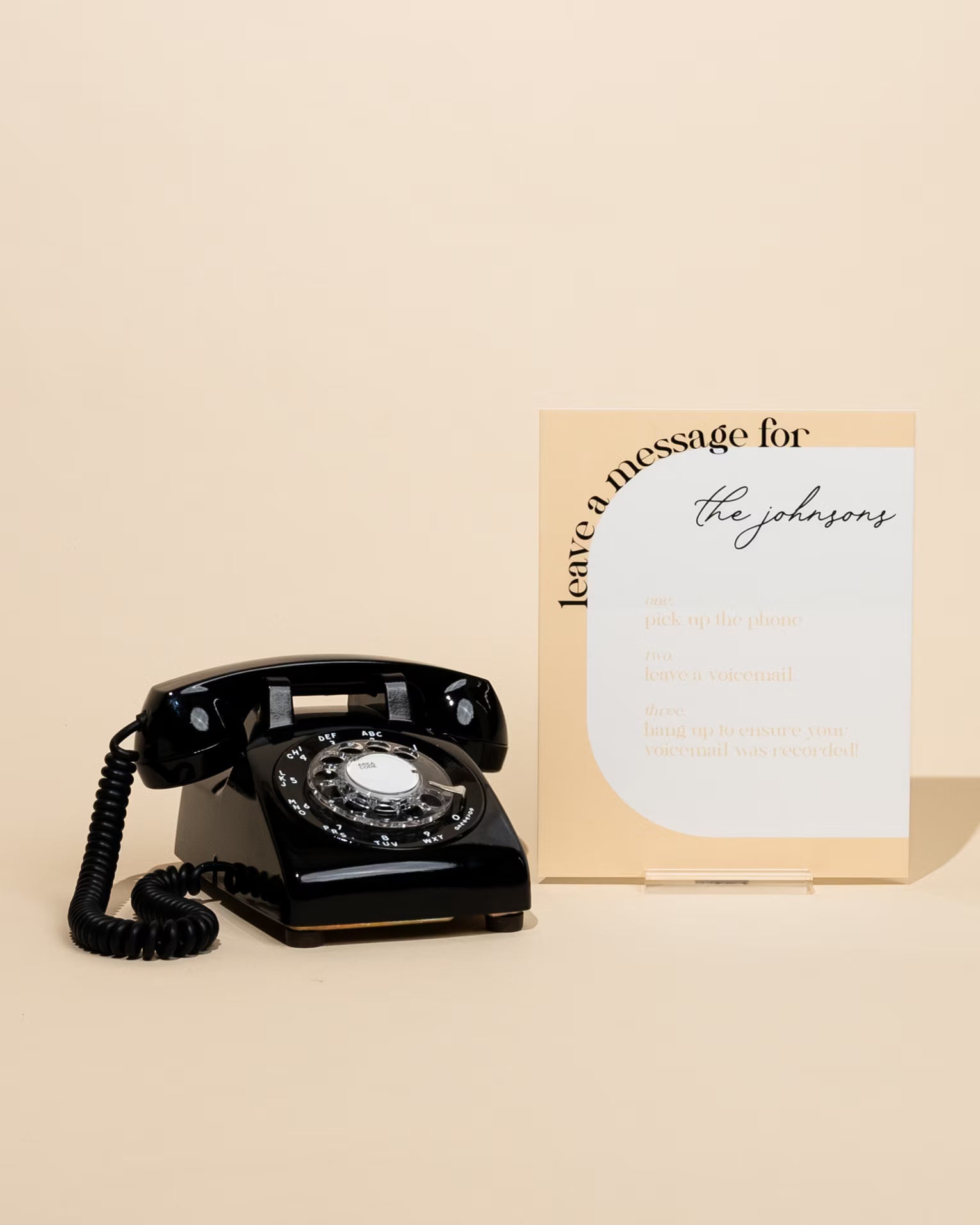 Vintage black rotary phone with a card on a beige background