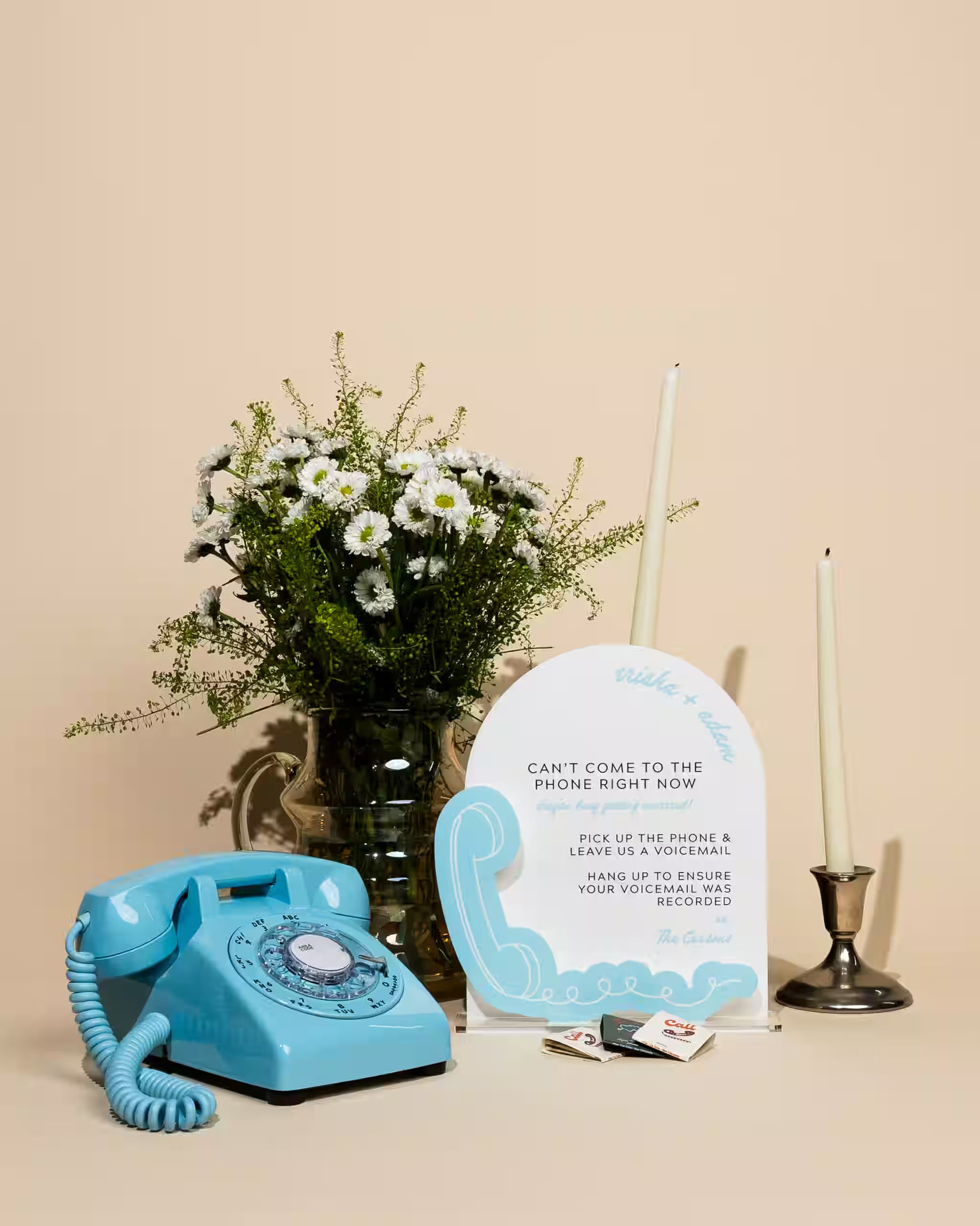 Vintage blue phone, bouquet of flowers, and sign on a beige background