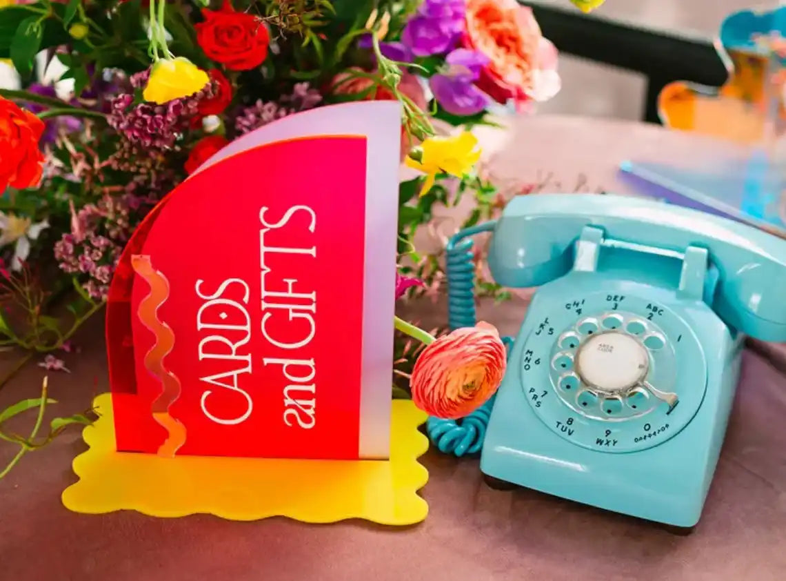 blue rotary phone on table next to a sign and flowers