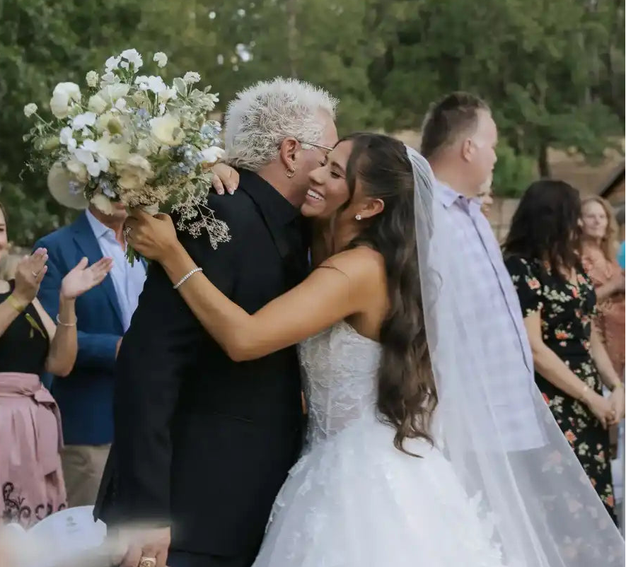 Couple embracing at a wedding with guests in the background