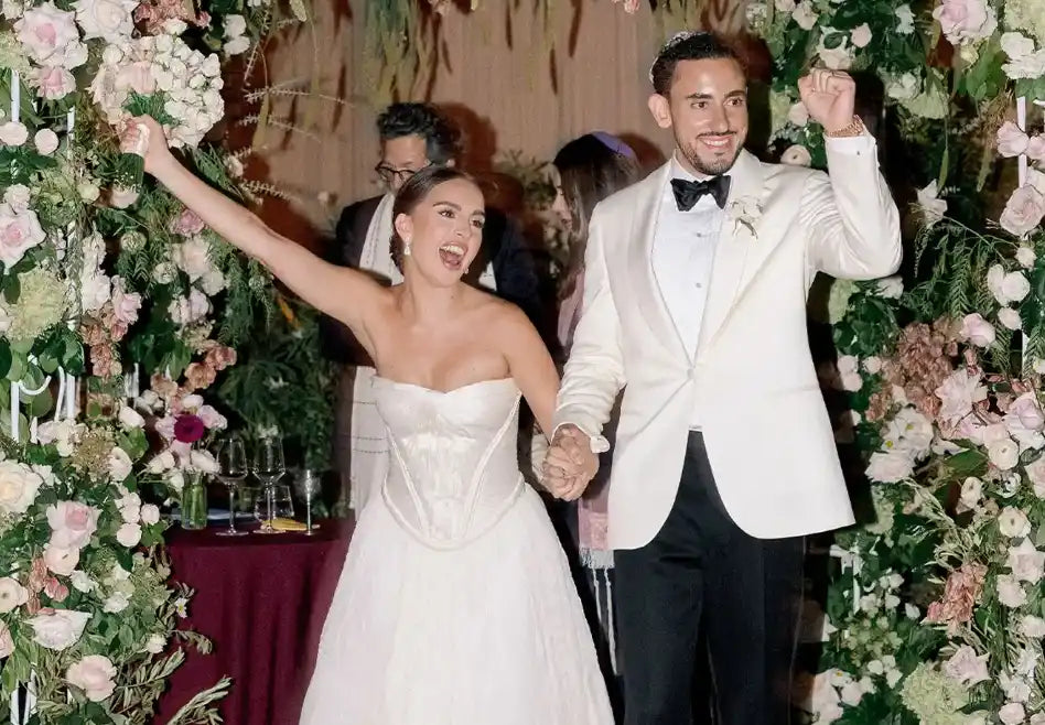 Wedding couple celebrating in front of a floral archway.
