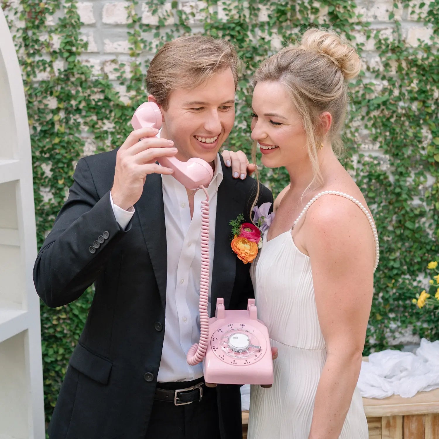 a man and woman holding a pink rotary phone.