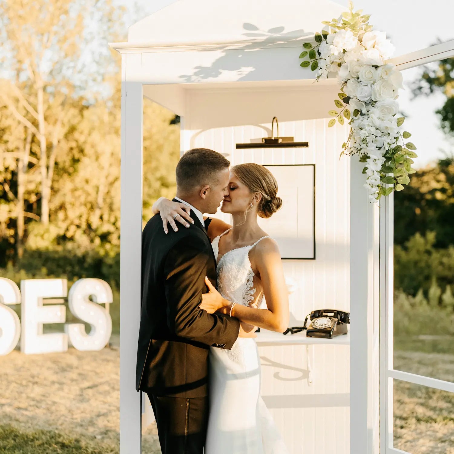 Couple embracing under a decorated archway with a black rotary phone