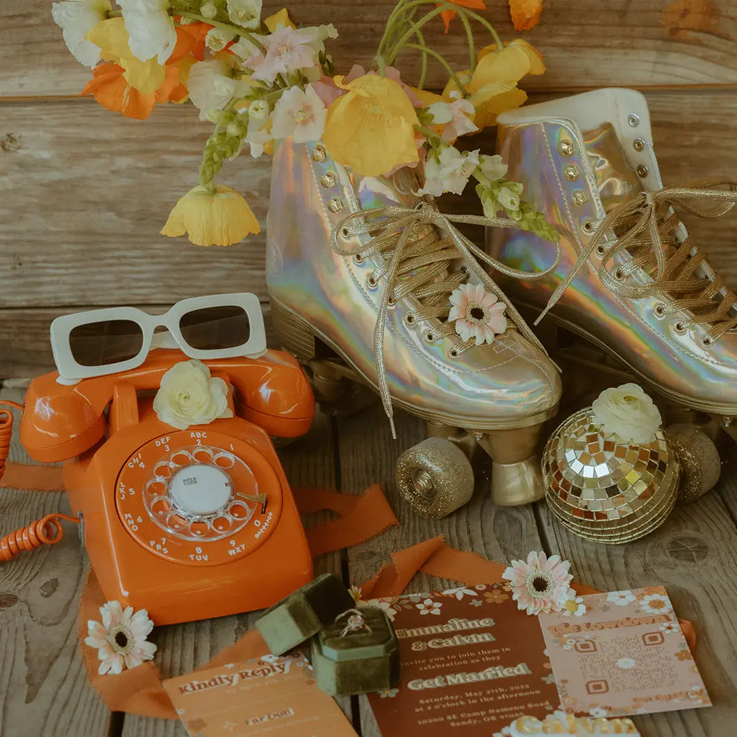 Decorative items including a vintage orange phone, iridescent roller skates, and flowers on a wooden surface.