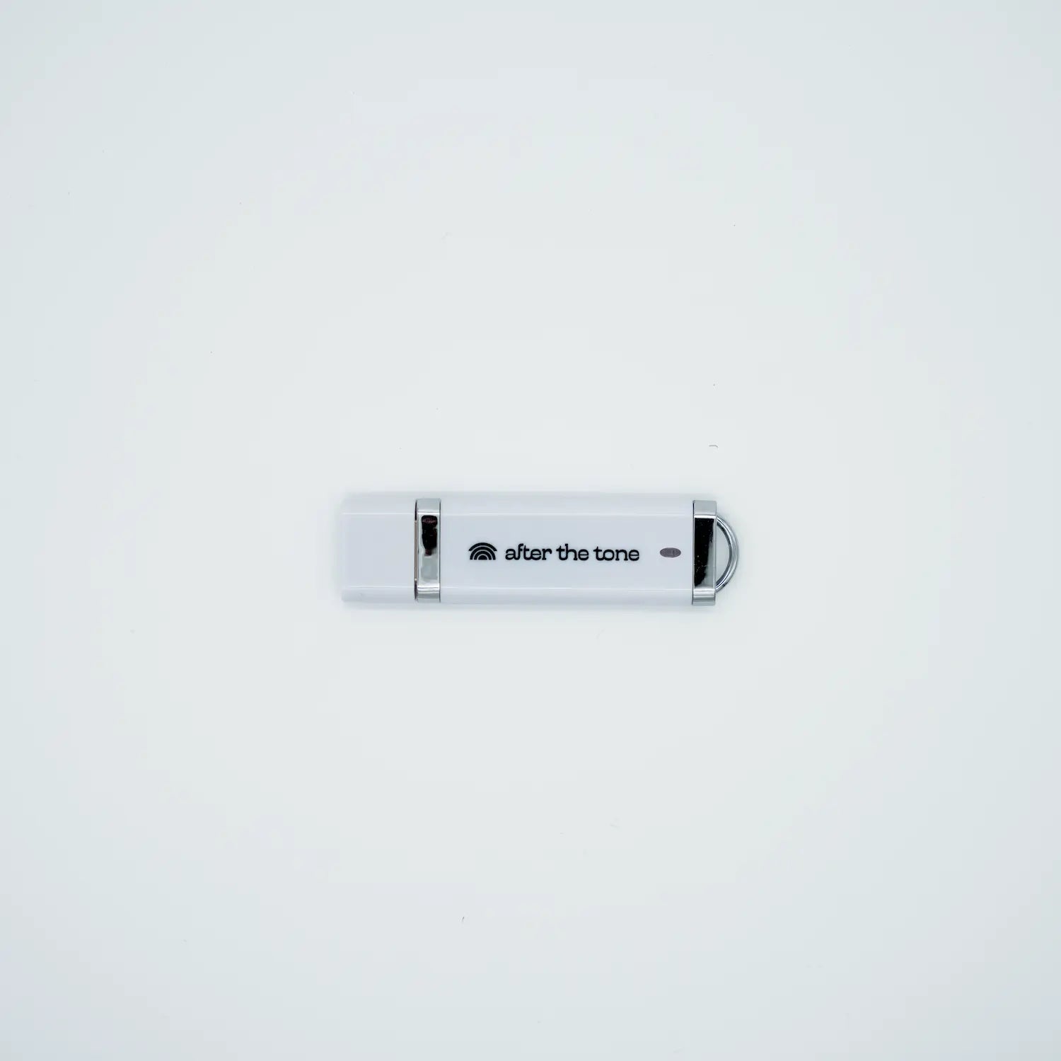 A white USB with the words "after the tone" on it