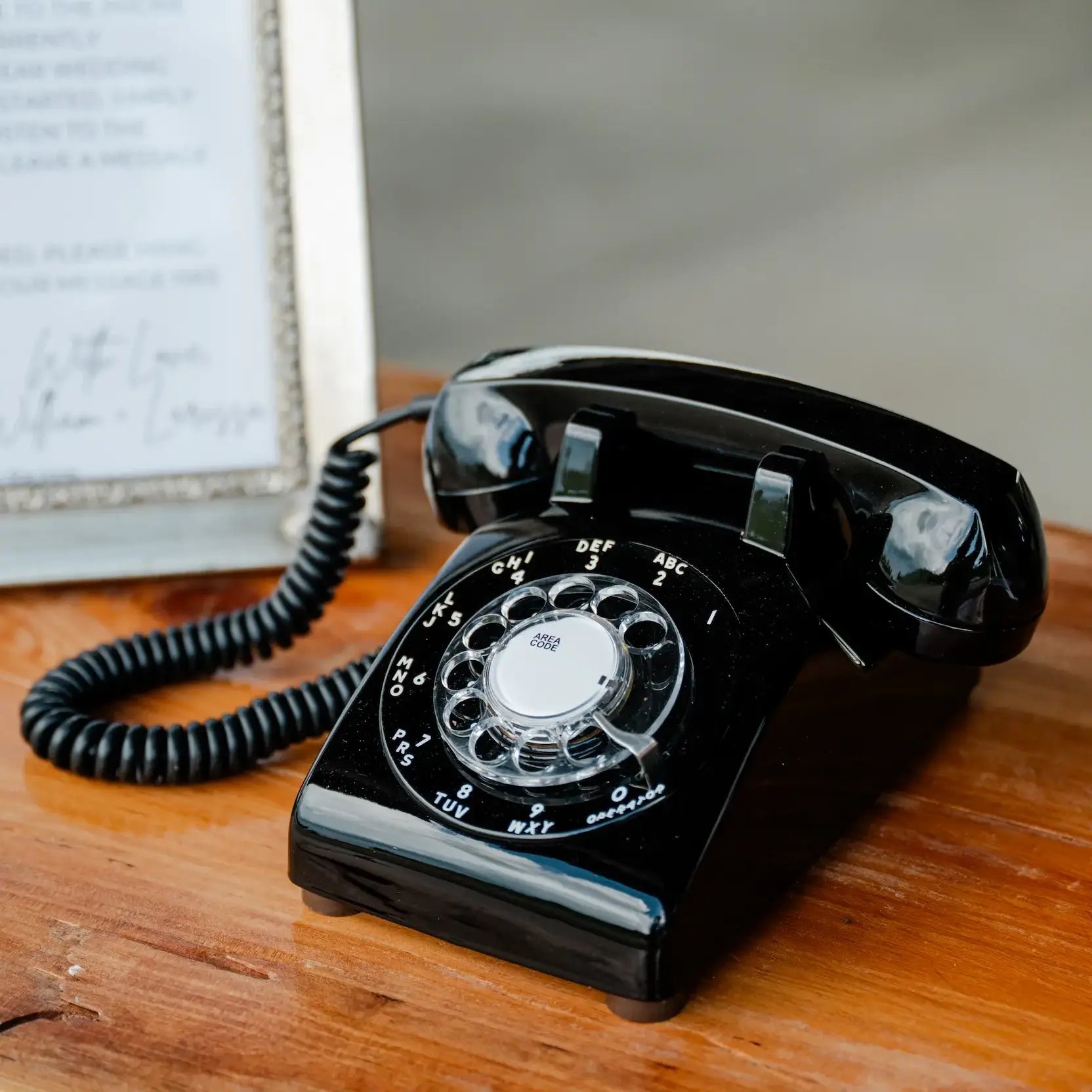 Vintage black rotary phone on a wooden surface with a blurred background