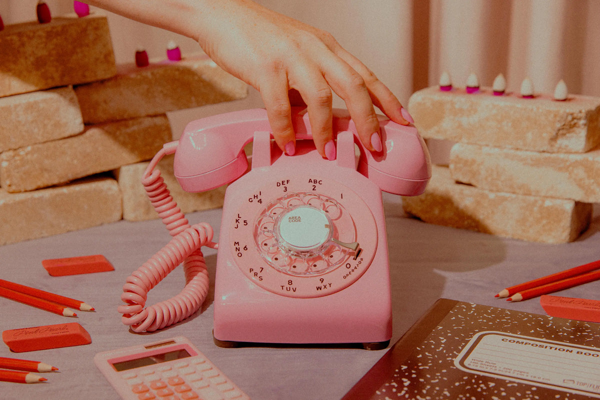 Pink rotary phone on a table with candles and snacks in the background