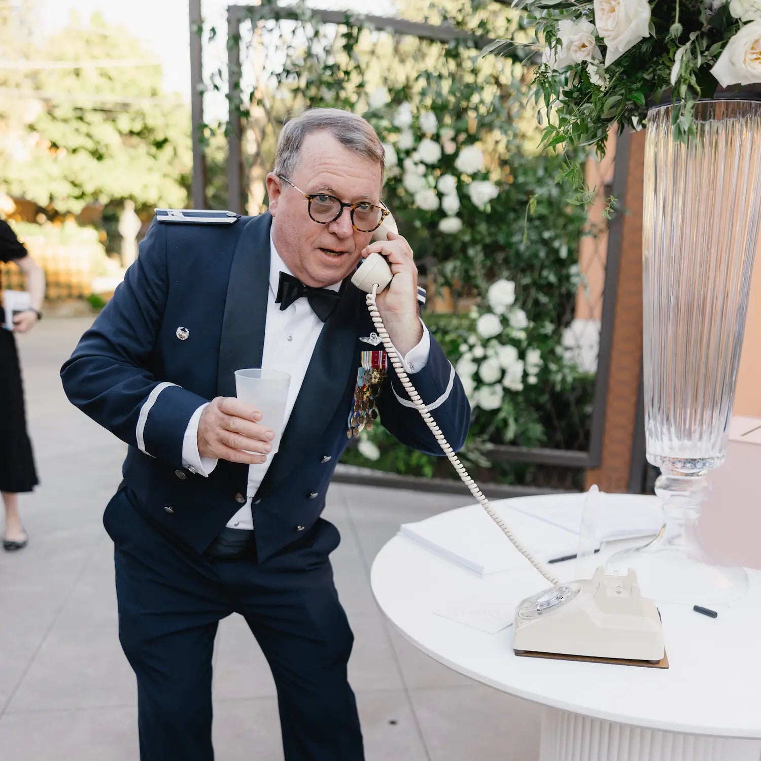 a man in a suit using a cream rotary phone on a table.