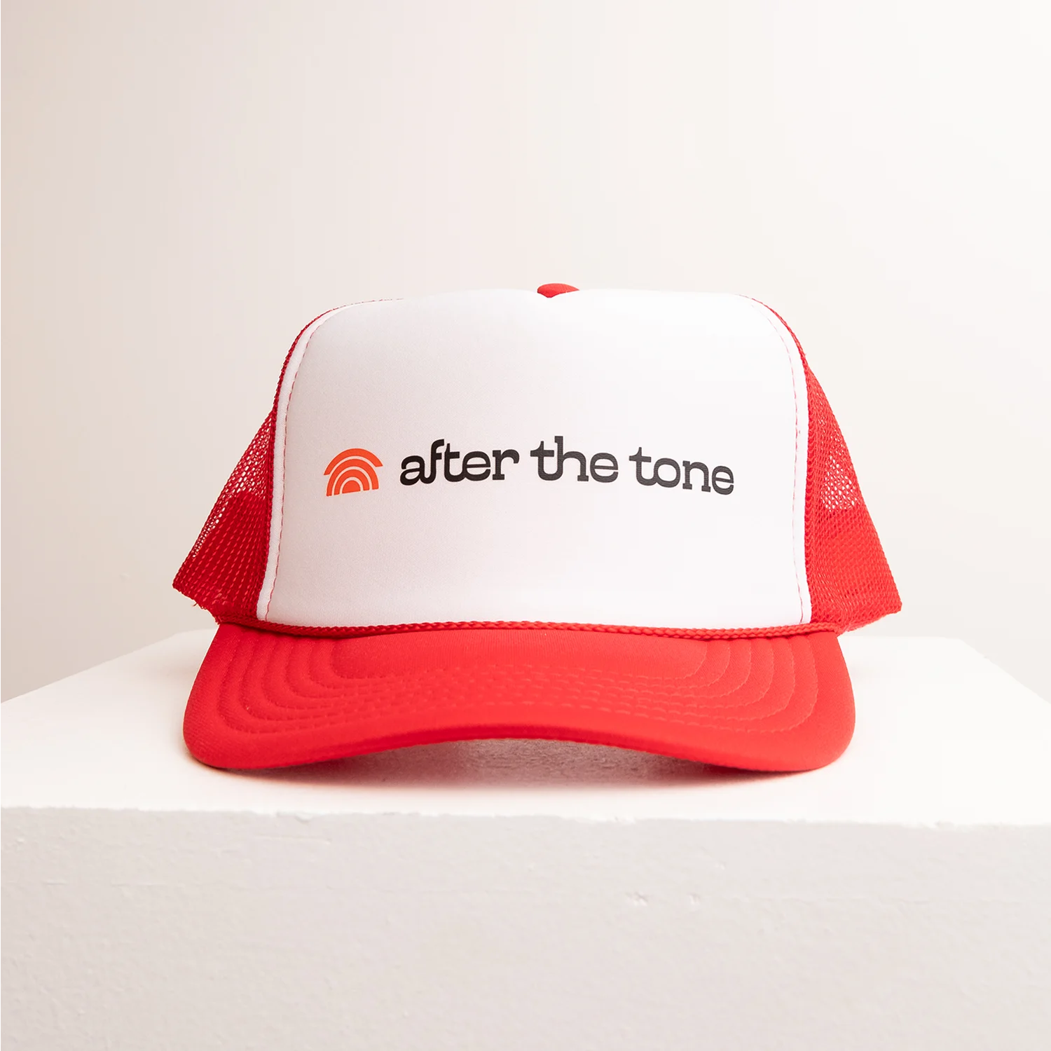 Red and white cap with 'after the tone' logo on a light background