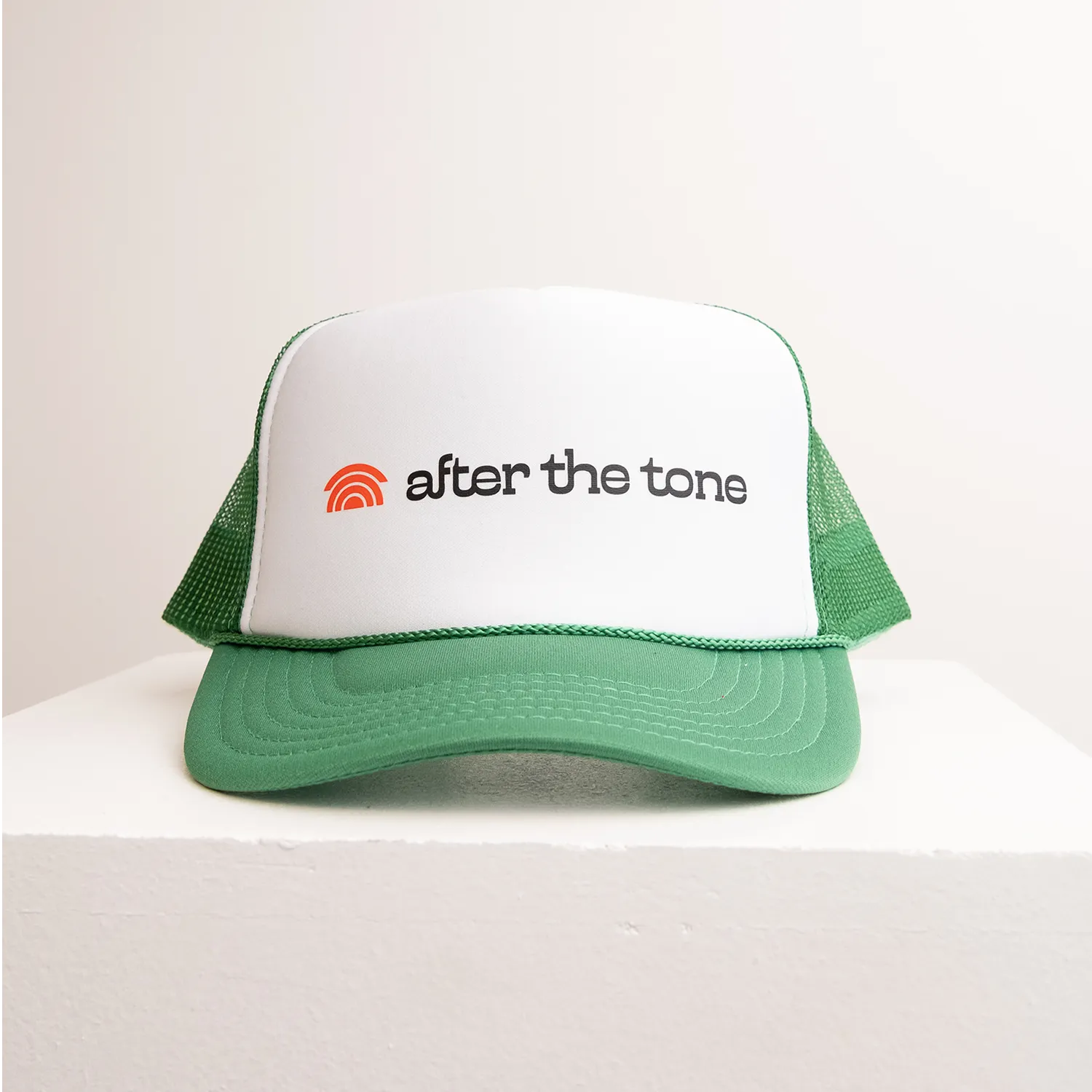 Green and white cap with 'after the tone' logo on a white background