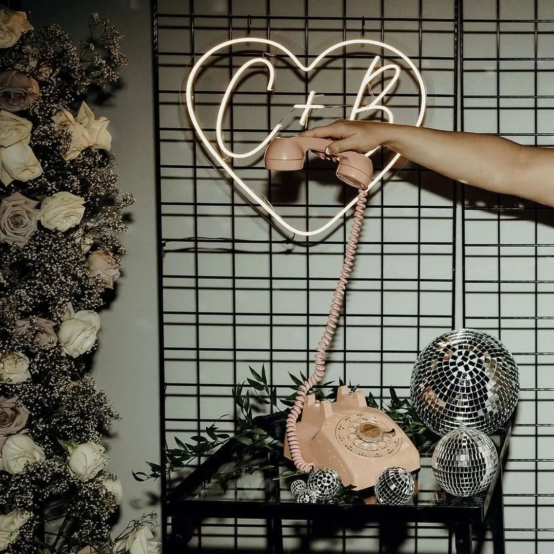 beige rotary phone being held on a black and glass table with black fence background