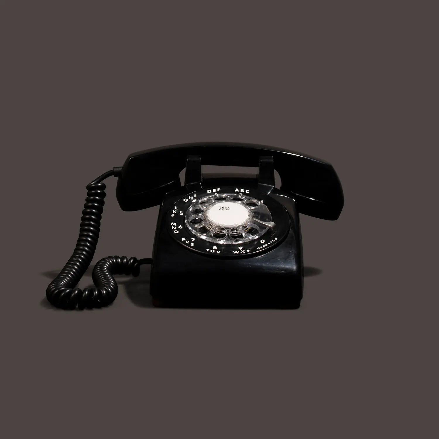 Black rotary phone on a gray background