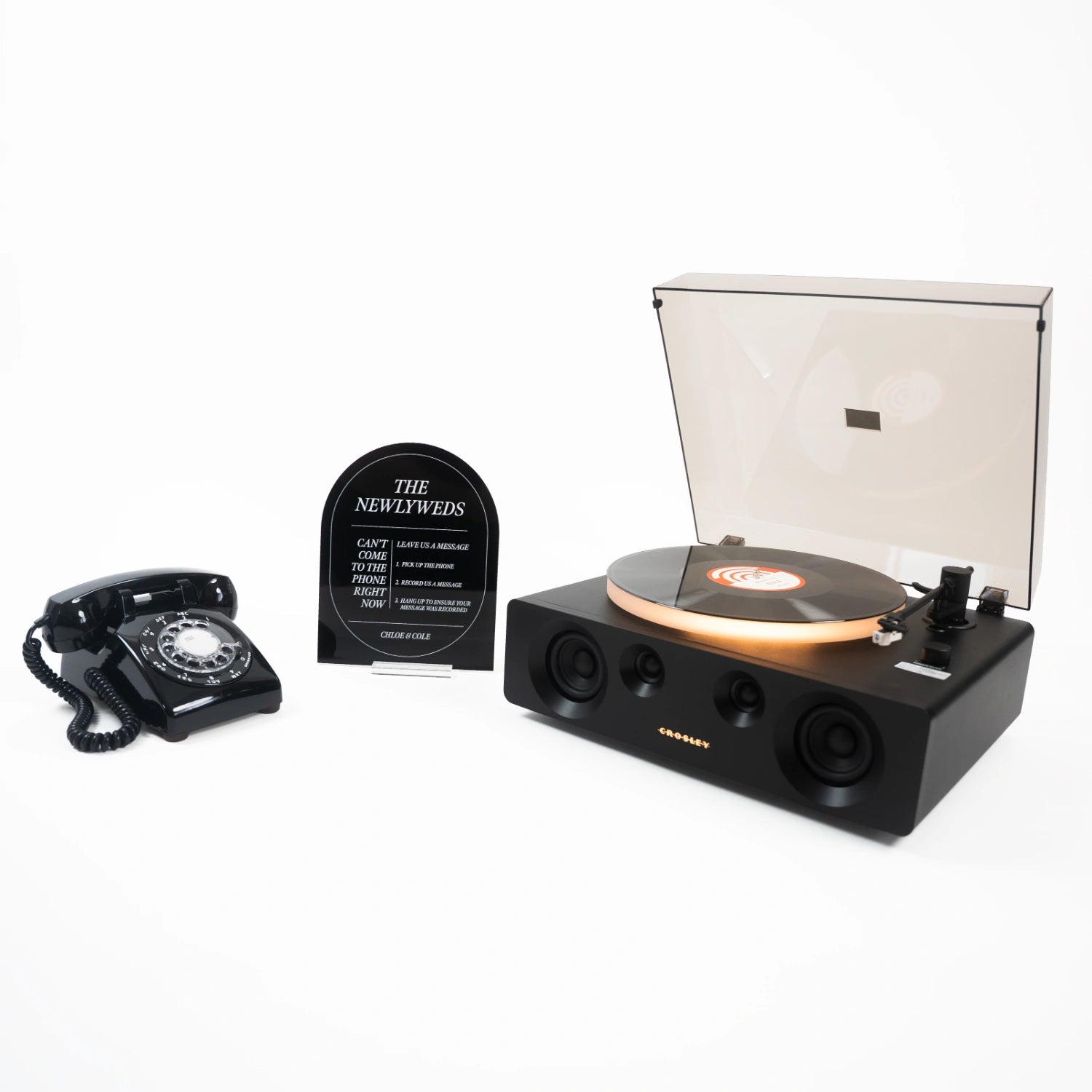 The Dylan bundle: a black rotary phone audio guestbook, a black Icon acrylic sign reading The Newlyweds, and a record player spinning a custom vinyl record.