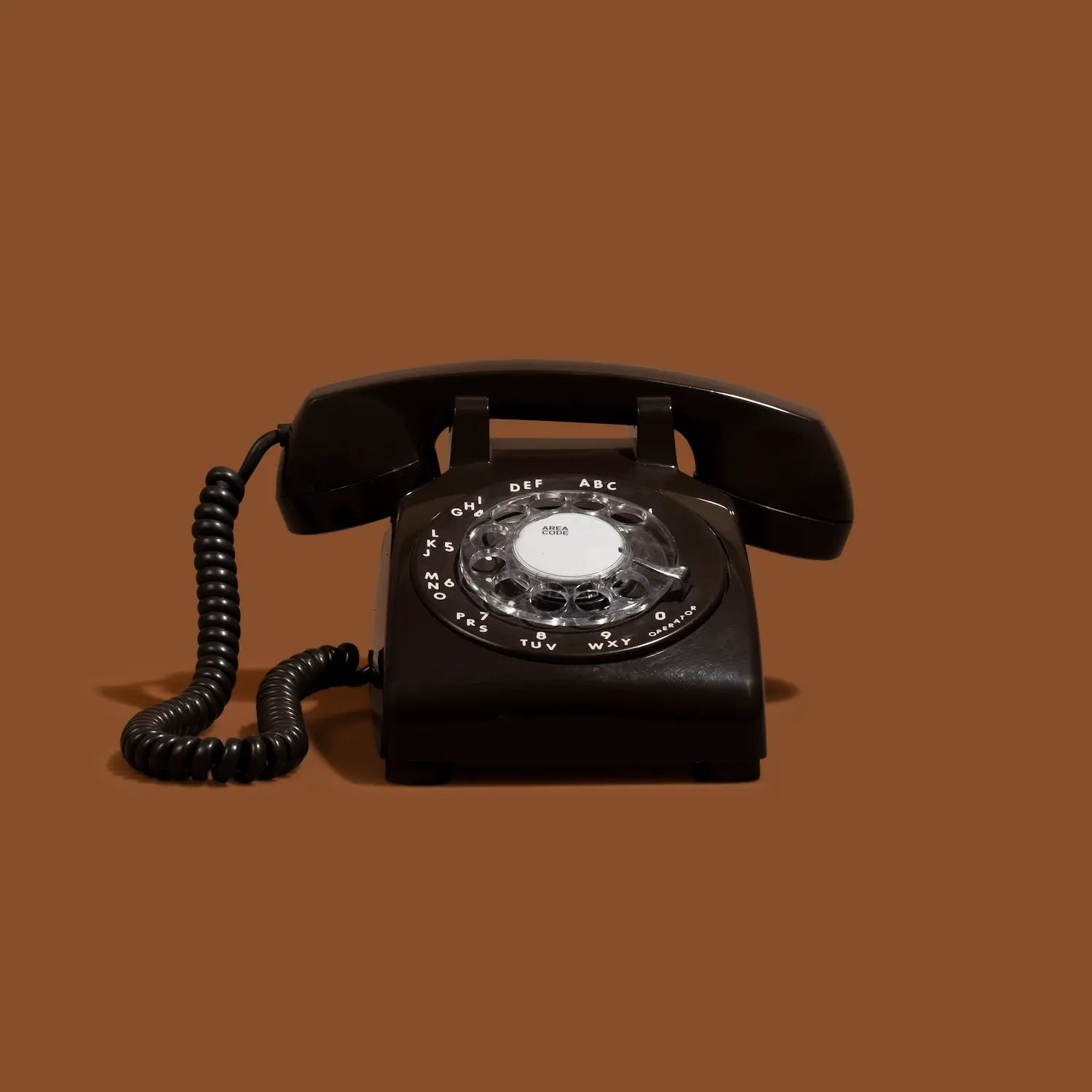 Black rotary phone on a brown background
