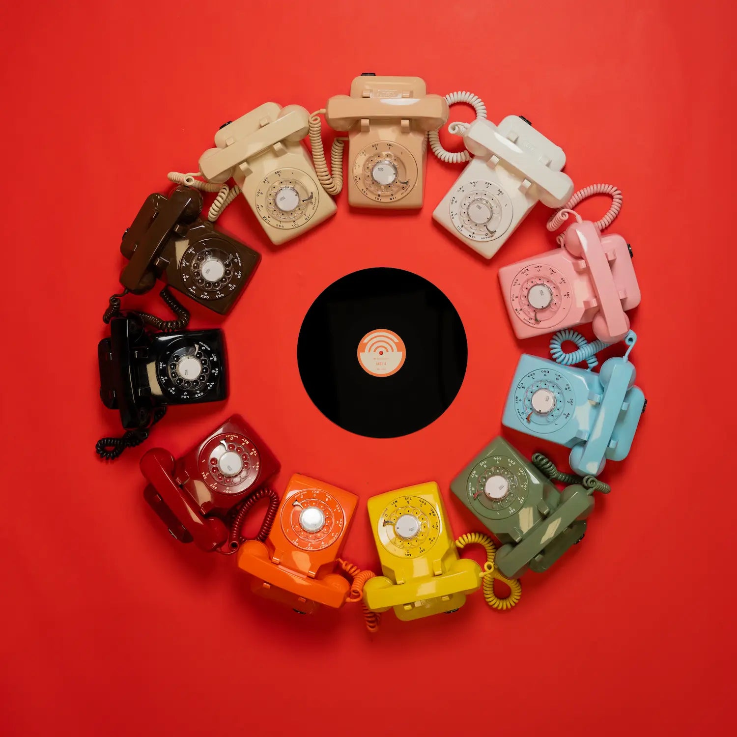 Colorful vintage telephones arranged in a circular pattern on a red background