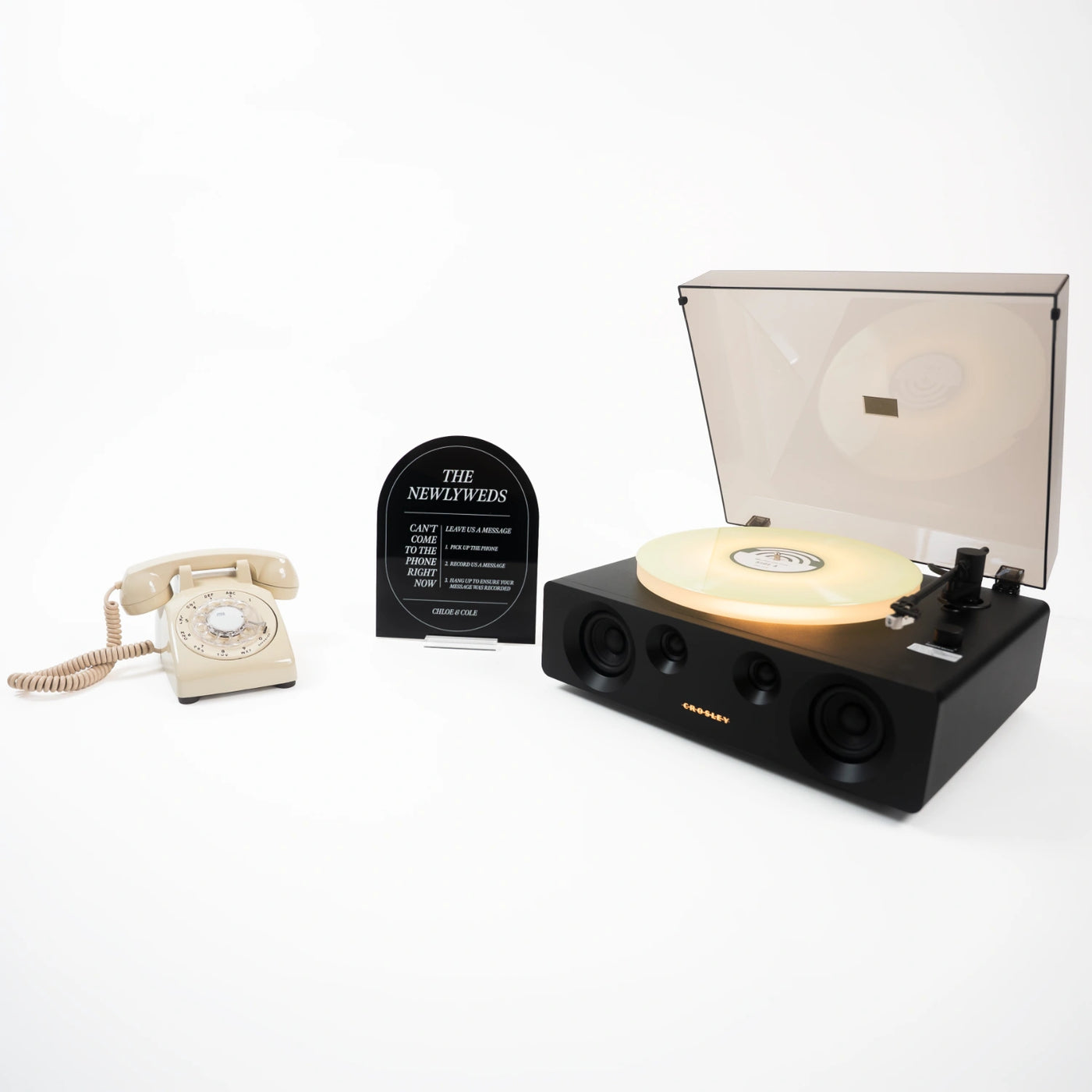 The Davis bundle: a cream rotary phone audio guestbook, a black Icon acrylic sign reading The Newlyweds, and a record player spinning a custom vinyl record.