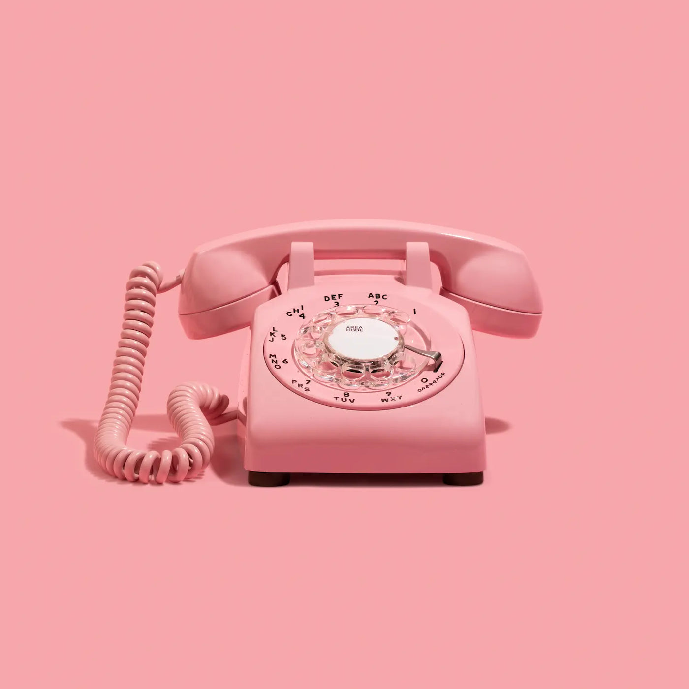 Pink rotary phone on a pink background