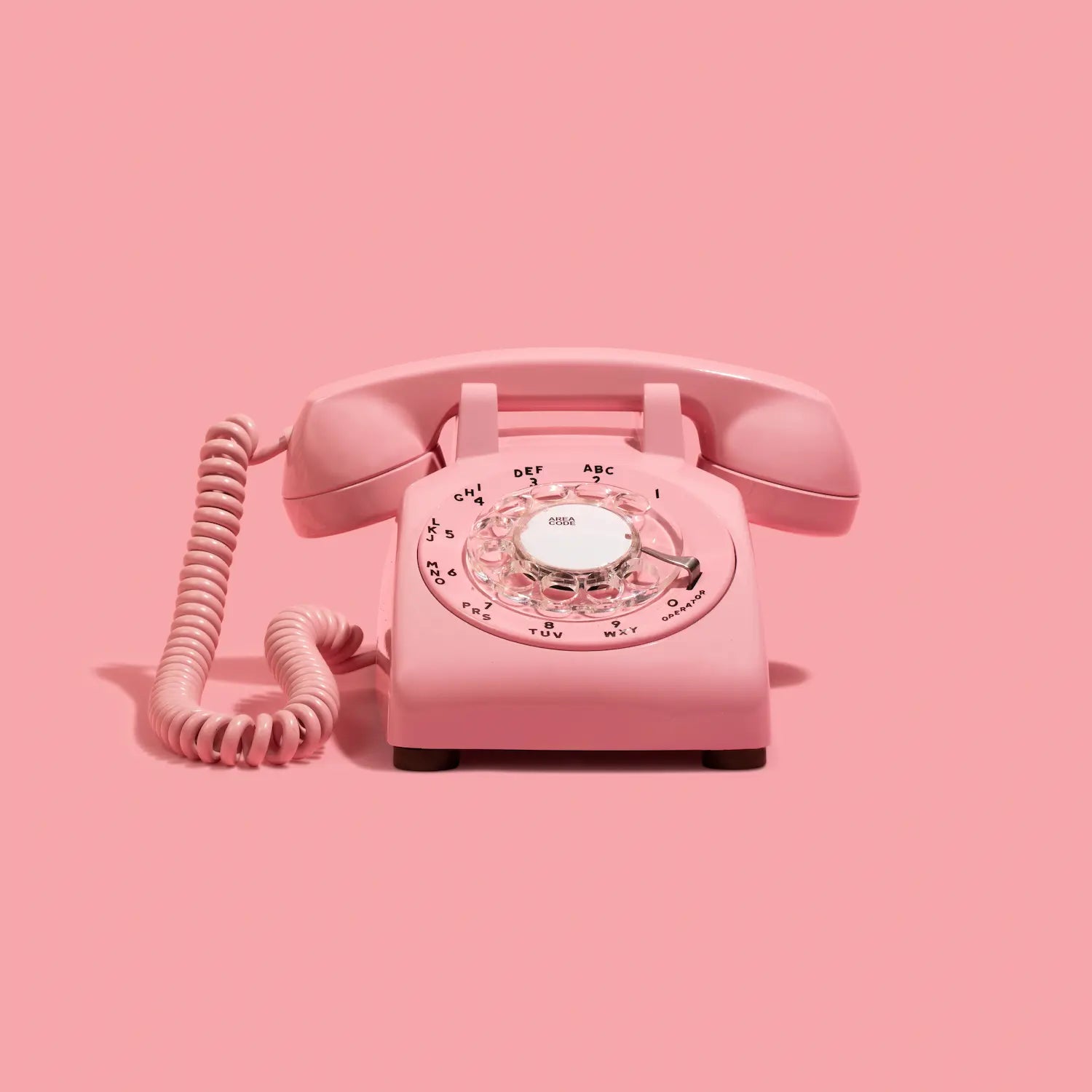 Pink rotary phone on a pink background