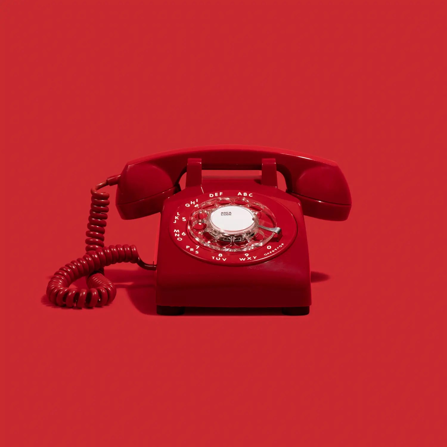 Red rotary phone on a red background
